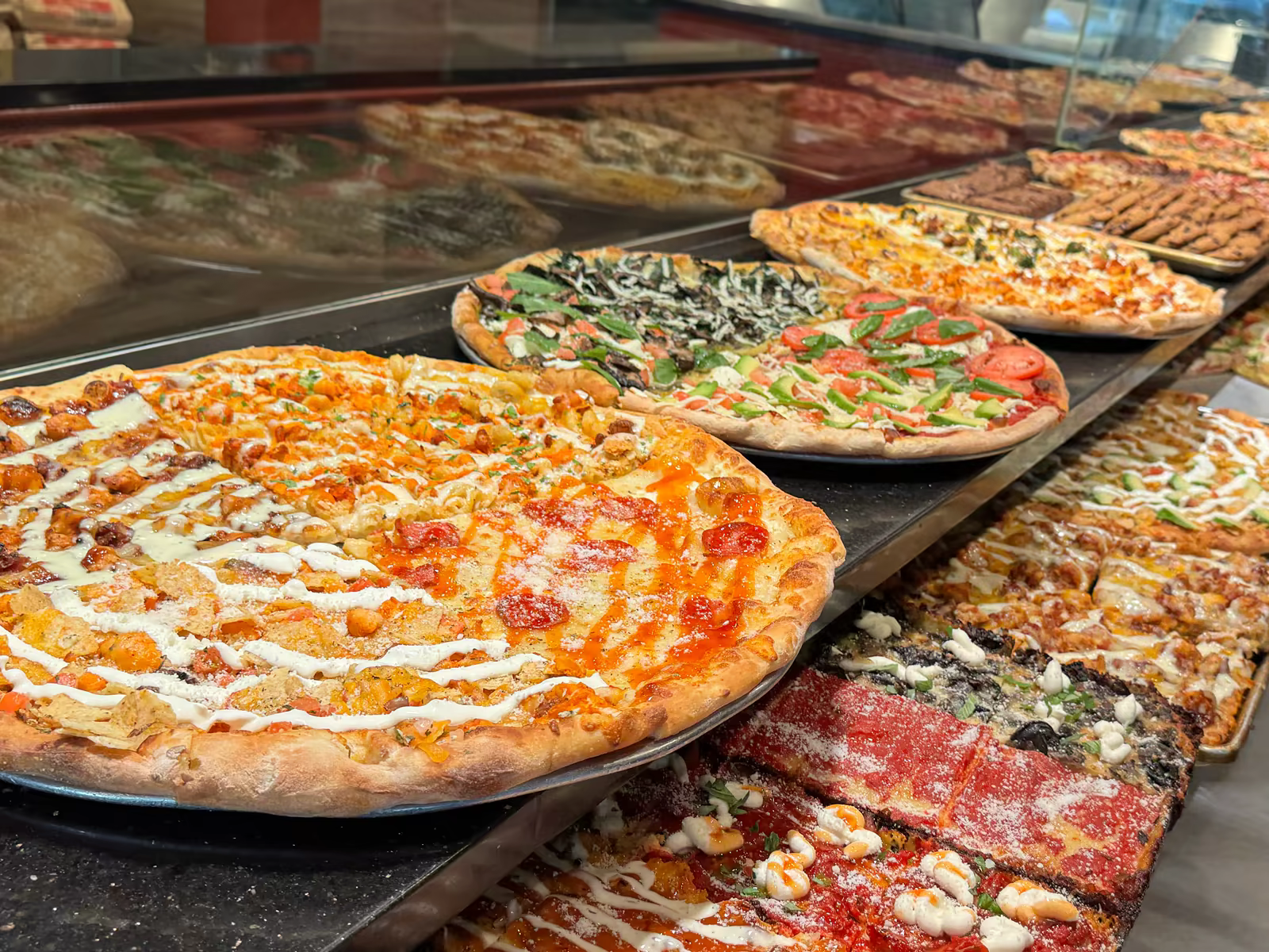 Round specialty pizzas and Sicilian slices in the display at Antonio's Pizza on Thayer Street in Providence