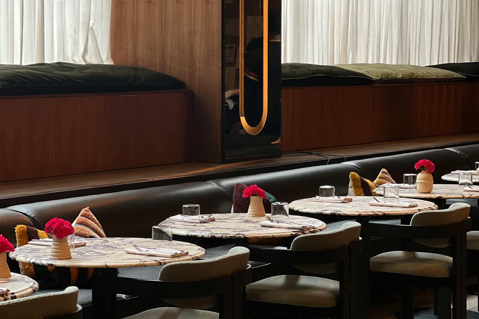Modern restaurant tables with wood seating and place settings